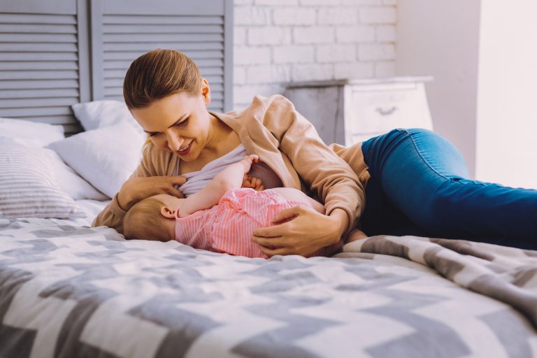 Calm woman smiling while breast breastfeeding her adorable baby